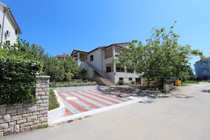 Houses with traditional architecture and balconies are surrounded by lush greenery and a well-maintained paved area.