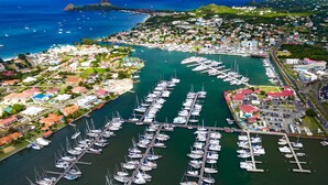An aerial view of a marina with numerous boats docked, surrounded by residential buildings and greenery. - Yacht Yota Bellavita (Gros Islet)