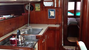 A compact kitchen with wooden cabinets, a sink, and a kettle. - Yacht Yota Bellavita (Gros Islet)
