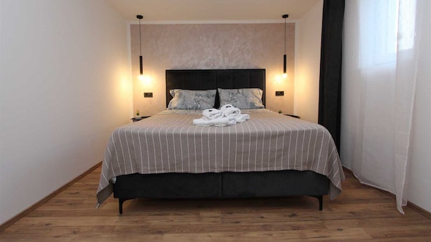 A modern bedroom with a large bed, two bedside lamps, and a headboard. - ENI One-Bedroom Apartment 1 (mali) (Rovinj)