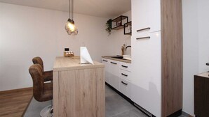 A modern kitchen with a wooden island, white cabinets, and a hanging light fixture. - ENI One-Bedroom Apartment 1 (mali) (Rovinj)