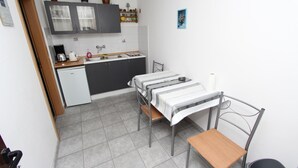 A compact kitchen with a sink, stove, and cabinets. There is a small dining table with two chairs. - ROSANNA One-Bedroom Apartment with Terrace 1 (Rovinj)