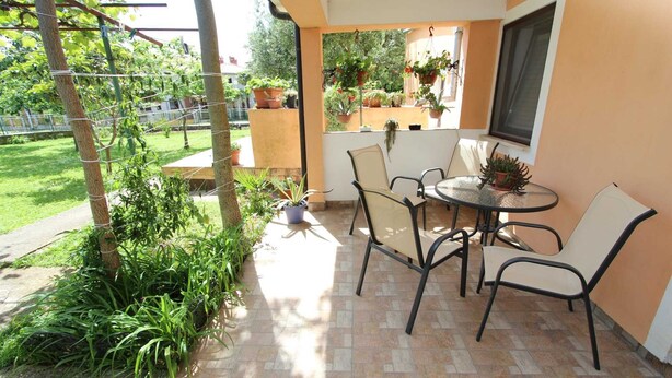 A patio with a table and chairs, surrounded by potted plants and a view of a garden. - ROSANNA One-Bedroom Apartment with Terrace 1 (Rovinj)