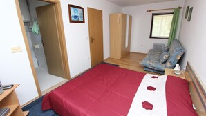 A bedroom with a large bed, a wooden wardrobe, a sofa, and a radiator. - ROSANNA One-Bedroom Apartment with Terrace 1 (Rovinj)