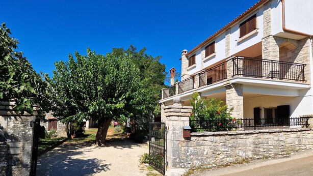 A two-story building with a stone facade, a balcony with a wrought iron railing, and a clear blue sky in the background. - GINA Two-Bedroom Apartment (Bale)
