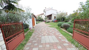 A paved pathway leading to a house with a red gate on both sides. - LILIANA One-Bedroom Apartment (Rovinjsko Selo)