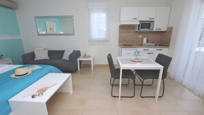 A compact hotel room with a bed, a small table, a kitchenette, and a seating area. - EMANUEL Studio with Balcony 3 (Rovinj)