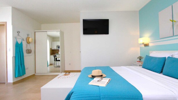 A hotel room with a bed, a TV, a desk, and a kitchenette. - EMANUEL Studio with Balcony 3 (Rovinj)