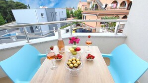 A balcony with a table set for two, featuring a bottle of wine, a glass, macarons, chocolates, and a vase of flowers. - EMANUEL Studio with Balcony 3 (Rovinj)