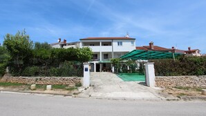 A two-story building with a red-tiled roof, a covered entrance, and a stone wall in front. - PALAZIOL Two-Bedroom Apartment 2 (Rovinj)