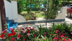 A garden with red and pink flowers, a wooden fence, and a view of parked cars and buildings in the background. - PALAZIOL Two-Bedroom Apartment 2 (Rovinj)