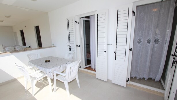 A room with a white table and chairs, a large mirror, and a sliding door with a patterned curtain. - PALAZIOL Two-Bedroom Apartment 2 (Rovinj)