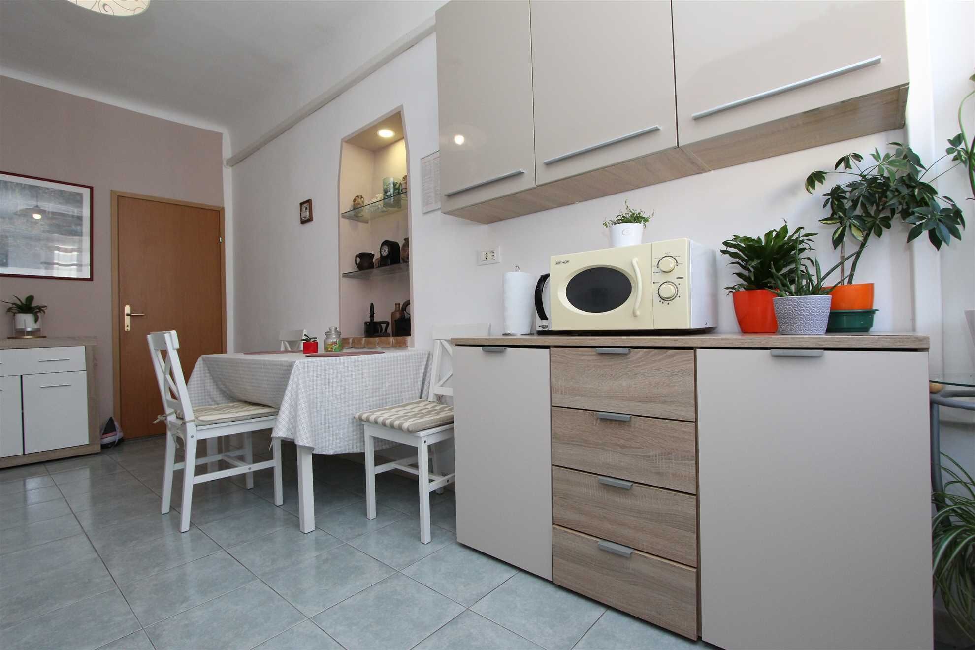A compact kitchen with a dining area, featuring a microwave, cabinets, and a small table with chairs.