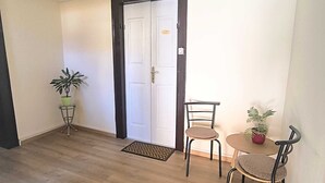 A room with a wooden floor, a white door, a small round table with two chairs, and a potted plant. - BAROCCO One-Bedroom Apartment (Rovinj)