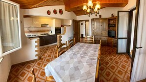 Une pièce chaleureuse comprenant une table à manger, des chaises, un coin cuisine et un plafond en bois.