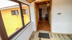 Un couloir avec un plafond en bois, une fenêtre avec des stores et un sol à motifs.