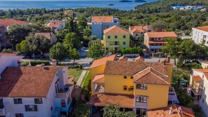Un quartier résidentiel où les maisons se distinguent par leurs toits recouverts de tuiles rouges, le tout étant entouré de verdure et offrant une vue dégagée sur la mer.