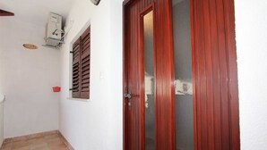 A hallway with a red door, a small window with shutters, and a wall-mounted electrical box. - MARUCHITA Two-Bedroom Apartment (Vesna, 1.kat) (Rovinj)