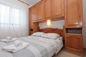 Une chambre à coucher comprenant un lit, des armoires en bois, une table de chevet et une lampe fixée au mur.