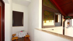 A small balcony with a table and two wooden stools, a window with a colorful view, and a wooden door. - MARUCHITA Two-Bedroom Apartment (Vesna, 1.kat) (Rovinj)