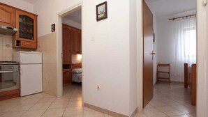 A kitchen with wooden cabinets, a refrigerator, and a dining area with a table and chairs. - MARUCHITA Two-Bedroom Apartment (Vesna, 1.kat) (Rovinj)