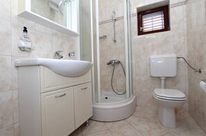 Une salle de bain avec un lavabo blanc, des toilettes et un espace douche.
