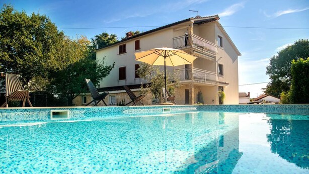 A swimming pool with a tiled edge, surrounded by lounge chairs and an umbrella. - VILLA FJORD Two-Bedroom Apartment 4 (Kanfanar)