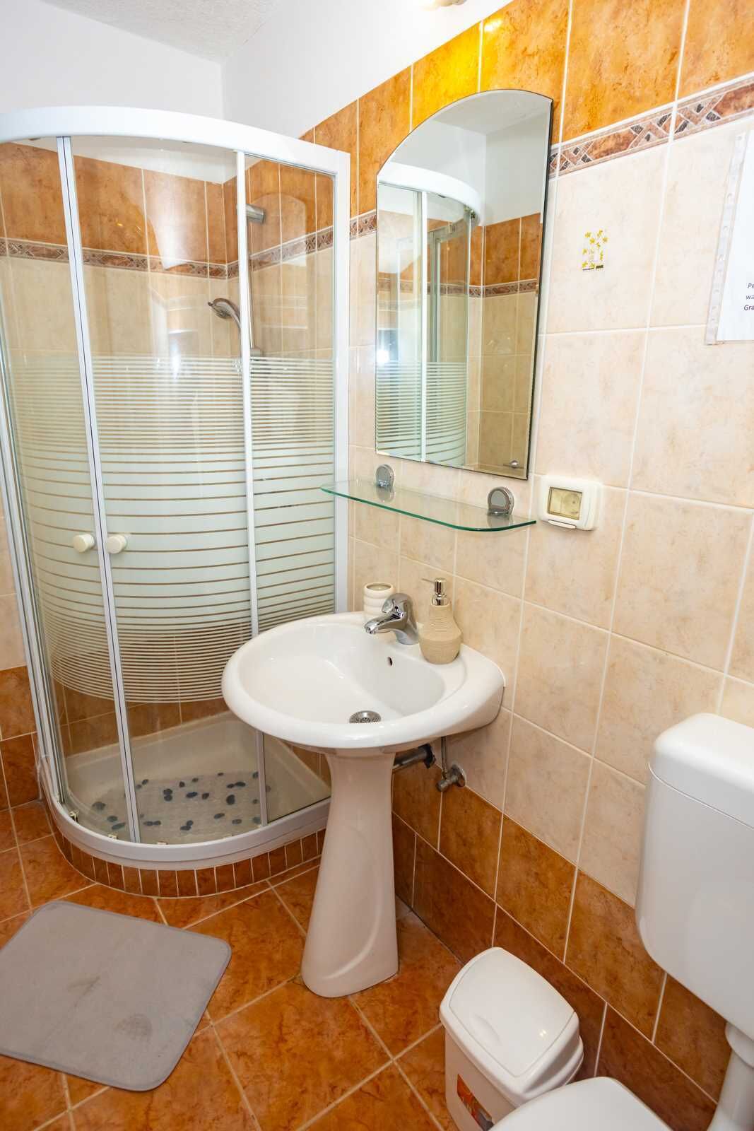 Ein Badezimmer mit Duschkabine, Waschbecken, Spiegel und Toilette.