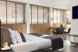 Moderni hotellihuone, jossa on sänky, työpöytä ja tuoli.