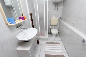 A modern bathroom with a white sink, a mirror, a toilet, and a shower area. - GOGA One-Bedroom Apartment with Terrace 1 (Rovinj)