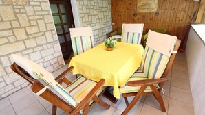 Un coin repas avec un mur en pierre, une porte en bois et une table entourée de chaises à rayures.