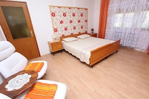 A bedroom with a wooden bed, a bedside table, a chair, and a door. - GOGA One-Bedroom Apartment with Terrace 1 (Rovinj)
