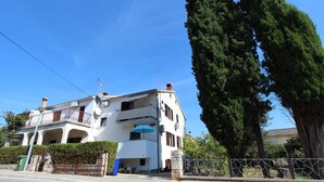 Ein zweistöckiges Gebäude mit Balkon, Satellitenschüssel und blauem Sonnenschirm.