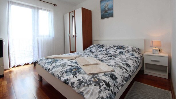 Ein Schlafzimmer mit einem Bett, einem Nachttisch, einer Lampe, einem Kleiderschrank und einem Bild an der Wand.