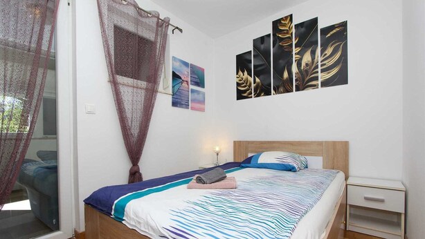 Una camera da letto con un letto, un comodino, una finestra con tenda e opere d'arte alle pareti.