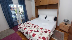 Un dormitorio con cama, cabecera de madera, mesitas de noche y una ventana con cortinas.