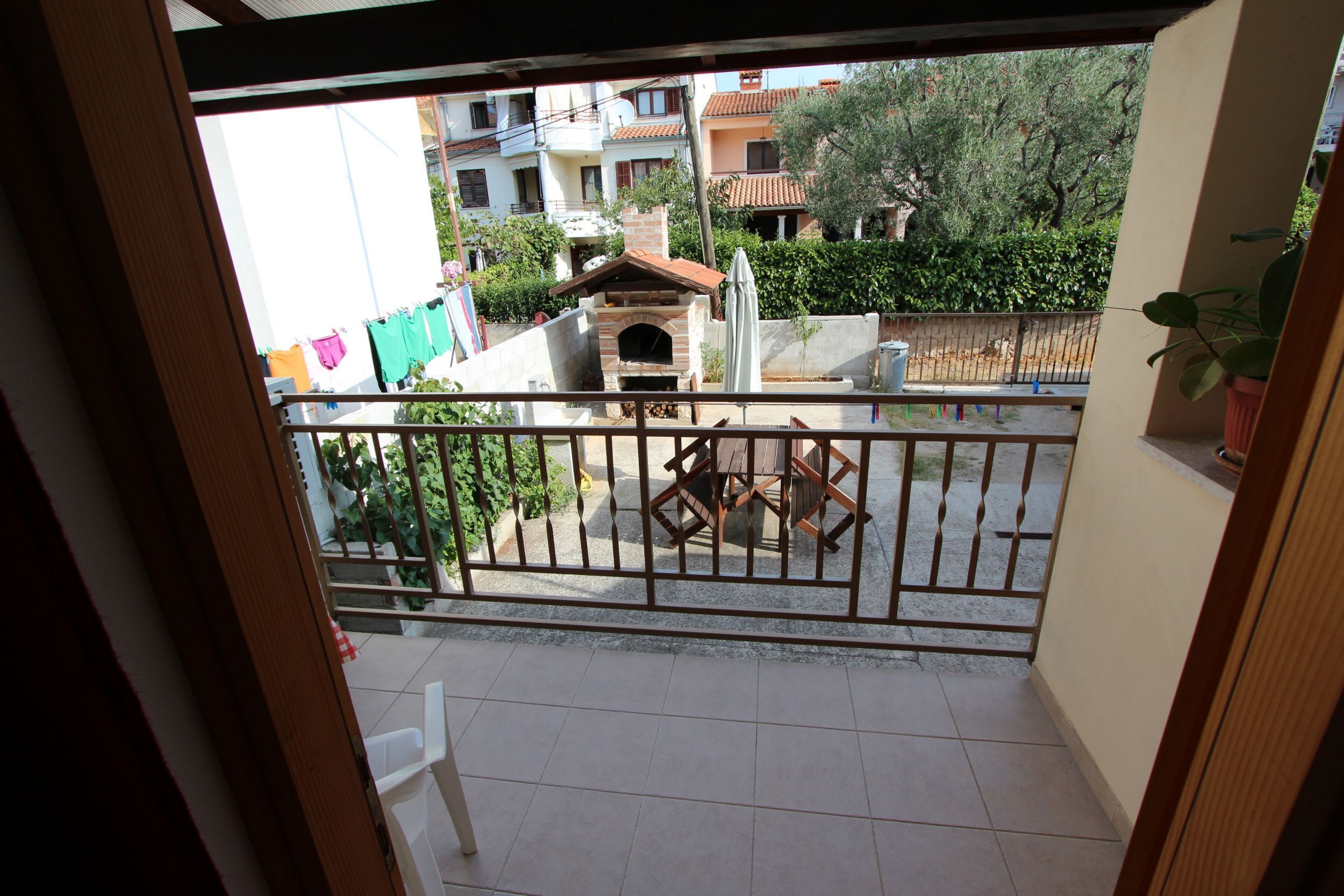 A balcony with a tiled floor, a small table, and a grill.