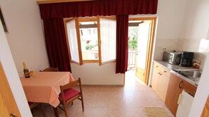 A compact kitchen with a dining table, chairs, a window with curtains, a coffee maker, and a refrigerator. - MARIZA Studio with Balcony (Rovinj)
