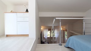 Un dormitorio con cama, escritorio y silla. Se ve una ventana con cortinas y vistas al exterior.