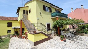 A yellow building with a staircase, outdoor seating, and potted plants. - STOJANA Two-Bedroom Apartment (Rovinj)
