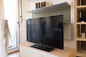 Relax in this comfortable living room with a flat-screen TV and a bookshelf.