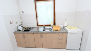 Una cocina compacta con estufa a gas, lavamanos y un refrigerador pequeño.
