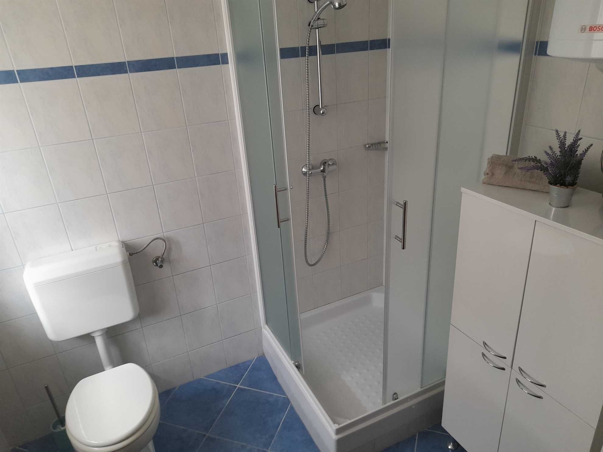 Une salle de bain comprenant des toilettes, un espace douche et un meuble de rangement.