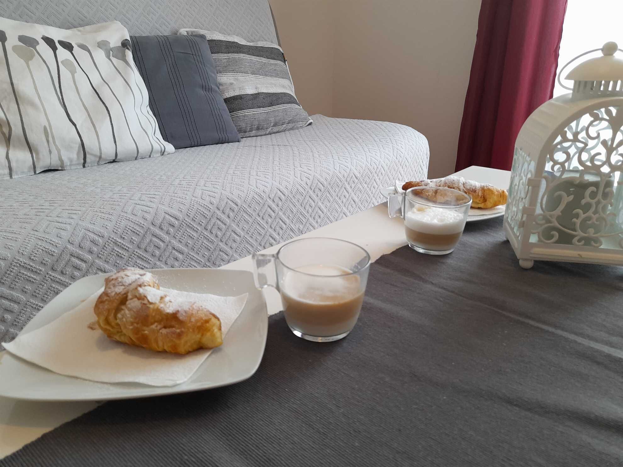 Een netjes gedekte ontbijttafel met gebak, een koffiemok en een glas melk.