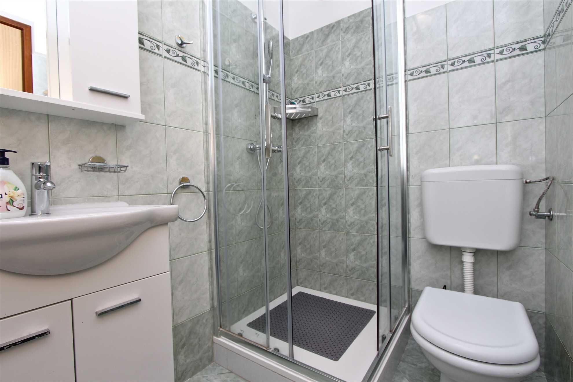Une salle de bain avec une douche à parois de verre, un lavabo blanc et des toilettes.