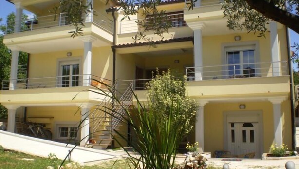 A two-story building with a balcony, a staircase, and a small garden area with a pond. - RAJCI One-Bedroom Apartment 2 (plavi) (Rovinj)