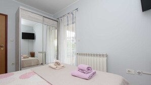 A bedroom with a bed, a mirror, a radiator, and a TV mounted on the wall. - RAJCI One-Bedroom Apartment 2 (plavi) (Rovinj)