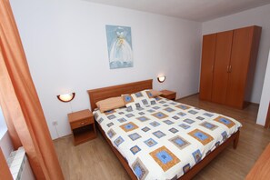 A bedroom with a wooden bed, nightstands, a wardrobe, and a wall-mounted light fixture.