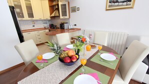 Taula de dinar preparada amb plats, coberts i un plat de fruita.