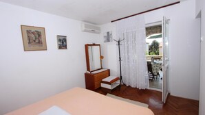 Ein Schlafzimmer mit Bett, Schminktisch, Spiegel und Fenster mit Ausblick.